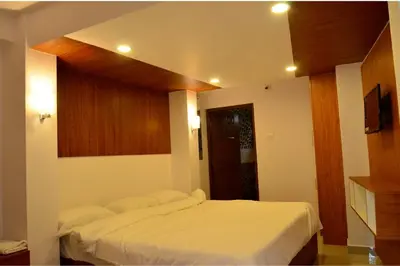 a bedroom with a white bed and a television at Hotel Magnet in Marayoor
