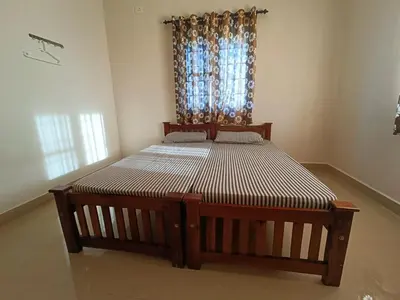 a large wooden bed in a room with a window at Shantham Service Apartments, Kinathukadavu, Coimbatore in Coimbatore