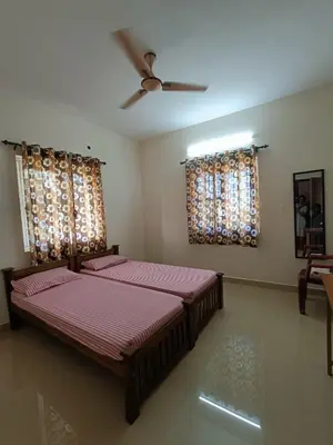 a bedroom with two beds and a ceiling fan at Shantham Service Apartments, Kinathukadavu, Coimbatore in Coimbatore