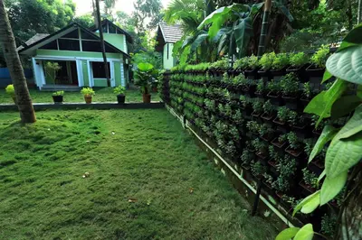 a fence with plants on it in front of a house at NARMADA HOMESTAY Yamuna in Malappuram