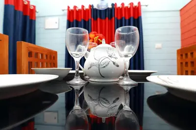 a table with three wine glasses and a vase on it at NARMADA HOMESTAY Yamuna in Malappuram
