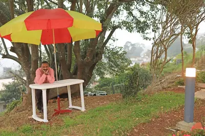 a man sitting on a table under an umbrella at HS Holiday Home in Coonoor