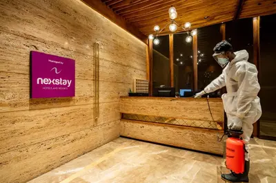 a man in a mask is standing in front of a counter at Nexstay Treats Inn in Kozhikode