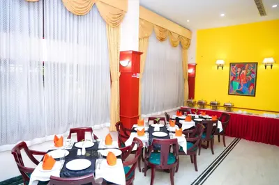 a dining room with tables and chairs and yellow walls at Fort Gate Hotels & Resorts in Trichūr