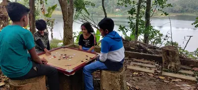 a group of people playing a game on a table at 7 Heaven Resorts in Ambalavayal