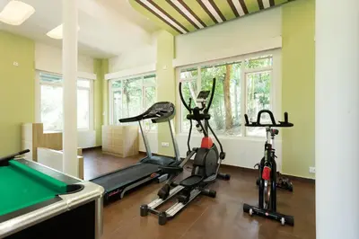 a gym with three exercise bikes and a pool table at The Woods Resorts Wayanad in Sultan Bathery
