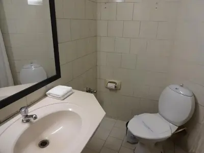 a bathroom with a sink and a toilet and a mirror at Manuelsons Malabar Palace in Kozhikode