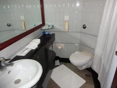 a bathroom with a sink and a toilet and a mirror at Manuelsons Malabar Palace in Kozhikode