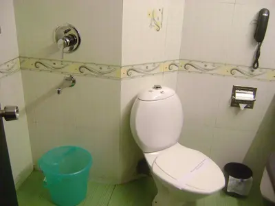 a bathroom with a toilet and a phone on the wall at Manuelsons Malabar Palace in Kozhikode