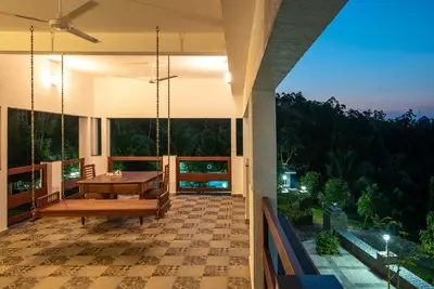 a house with a porch with a table and swings at StayVista at Springhills Villa & Ayurvedic Spa in Cochin