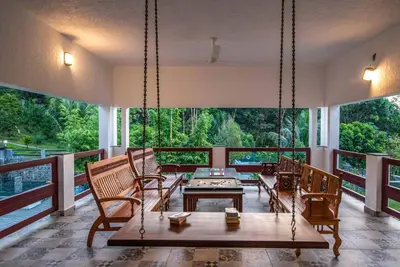 a porch with a swing and a table and chairs at StayVista at Springhills Villa & Ayurvedic Spa in Cochin
