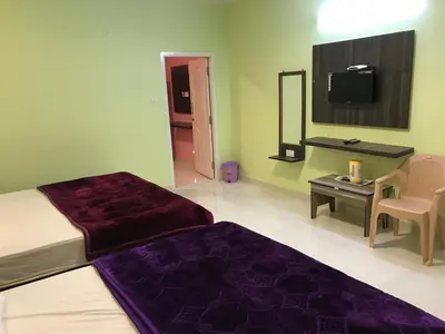 a bedroom with two beds and a mirror and a tv at HAPPYSTAY rooms and cottages in Ooty