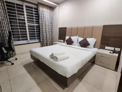 a bedroom with a large white bed and a window at Neermala Residency in Coimbatore