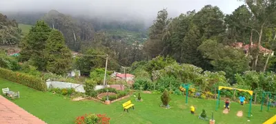 a park with a playground with people in the grass at Yantra Resort, Ooty in Ooty
