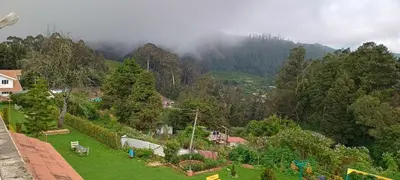 a view of a mountain with trees and a town at Yantra Resort, Ooty in Ooty