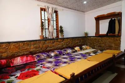 a large bed in a room with a stone wall at Bison Valley Estate in Vālpārai