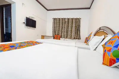 a room with three beds and a television at Hotel Orchid Inn in Ooty