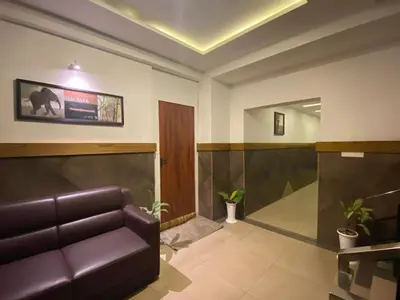 a waiting room with a leather couch and a tv at THE PORCH INN in Wayanad