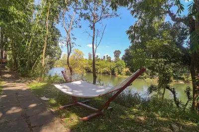a chair sitting on the side of a river at 5BR Firefly By The River with Breakfast - Nature's Lap in Kushālnagar