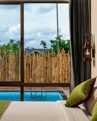 a bedroom with a view of a swimming pool through a window at Coffee Greens Resort in Wayanad