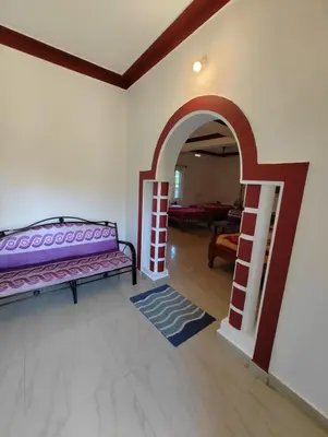 a living room with a bed and an archway at Coorg Nest Cottages By Dreamy Vacations in Kushālnagar