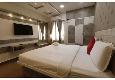 a bedroom with a large white bed and a flat screen tv at SR BOUTIQUEE STAY in Coimbatore