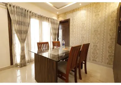 a dining room with a wooden table and chairs at SR BOUTIQUEE STAY in Coimbatore