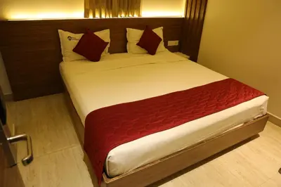 a bedroom with a large bed with red sheets and pillows at Hotel Amoha in Palani