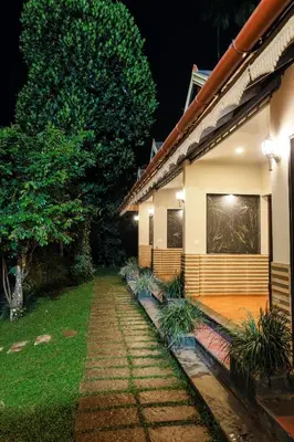 a house with a pathway in front of it at night at Hill Rows Plantation and Forest Experience By GreenEscapes in Vythiri