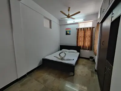 a small room with a bed and a ceiling fan at Yoga House in Vānivilāsa Puram