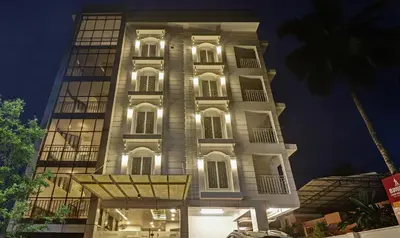 a tall white building with lights on at Sreepathi Mayoogha in Guruvāyūr