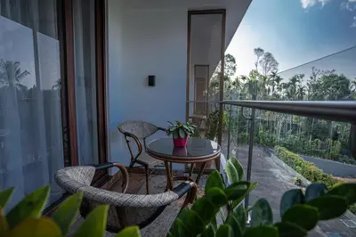 a balcony with a table and chairs and some plants at Saugandhika West Gate in Wayanad