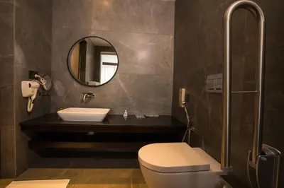 a bathroom with a toilet and a sink and a mirror at Saugandhika West Gate in Wayanad