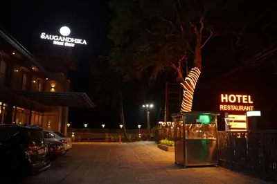 a hotel at night with a hotel sign and a parking lot at Saugandhika West Gate in Wayanad