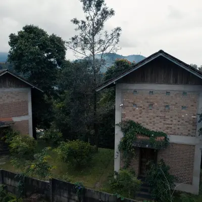 a house with a brick wall next to a fence at BARSATI Ranches in Vythiri