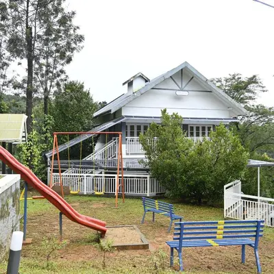 a playground with a slide and two benches in front of a house at Riviera inn resort in Chillithodu