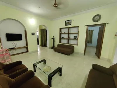 a living room with two couches and a tv at Kavitha House Homestay in Mysore