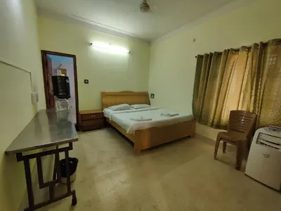 a bedroom with a bed and a table and a desk at Kavitha House Homestay in Mysore
