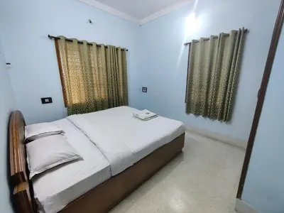 a small bedroom with a bed and two windows at Kavitha House Homestay in Mysore