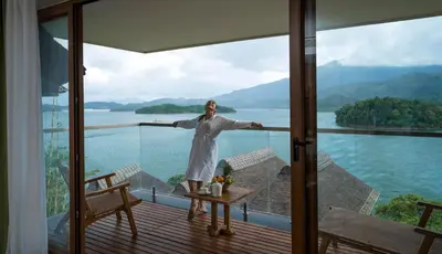 a woman standing on the balcony of a house at MOUNTAIN SHADOWS RESORT Wayanad in Wayanad