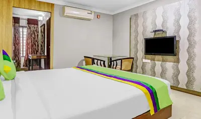 a bedroom with a white bed and a tv at Treebo Symphony Hotels And Resorts Angamally in Kizhake Chālakudi