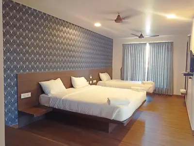 a bedroom with two beds and a large window at HOTEL VINTAGE CASTLE in Coimbatore