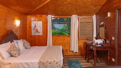 a bedroom with a bed and a table and a window at De Rock Jungle Living Resort in Coonoor