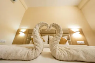a pair of towel swans sitting on a bed at TAG HOTELS in Irugūr