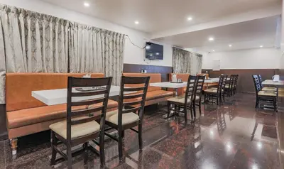 a dining room with tables and chairs and a television at The Baron in Ooty