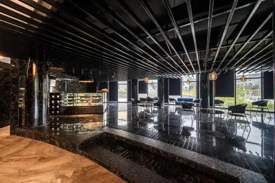 a lobby with black walls and tables and chairs at Fezinn Hotel - Best Wayanad Hotel in 2024 in Kozhikode