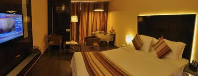 a hotel room with a bed and a television at The Arcadia Coimbatore Airport in Coimbatore