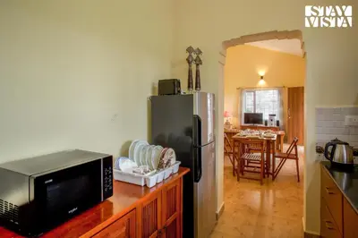 a kitchen with a microwave and a refrigerator at StayVista at Zolas Retreat 2BHK Pet Friendly and Breakfast Included in Coonoor