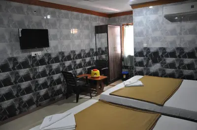a room with two beds and a table and a tv at C M HOTEL NEW in Wodapatti