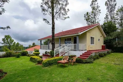 a small yellow house with a porch and a yard at StayVista at Casa Pinnacle - Pet Friendly Home with Lawn in Coonoor